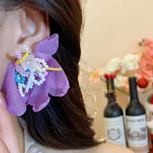 Detailed view of purple chiffon flower earrings decorated with colorful glass beads