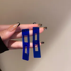 Primo piano di orecchini geometrici in resina blu Klein in stile francese vintage