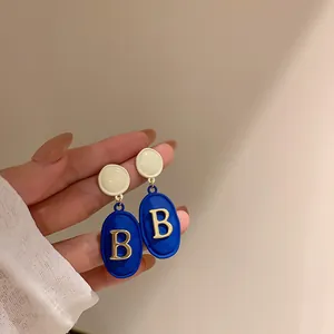 Vista dettagliata di orecchini a goccia ovali blu reale con decorazione a lettera B