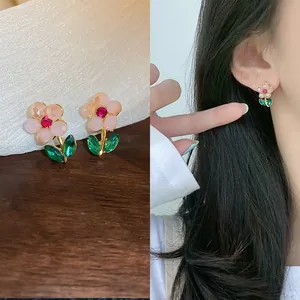 Detail shot of pink flower earrings with green crystal leaves and model wearing