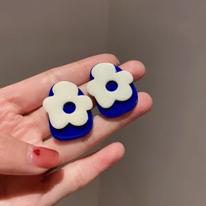 Primo piano di orecchini blu Klein in stile francese con dettaglio floreale bianco