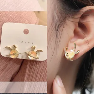 Detailed view of gold rabbit planet earrings with sparkling zircon on ear and display card.