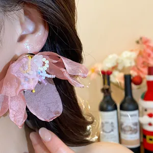Close-up of pink chiffon flower earring with delicate glass bead details on a model