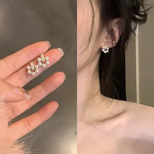 Detail view showing elegant mini pearl earrings with zircon accents and on-ear wear