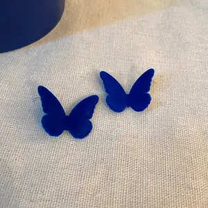 Vista dettagliata degli orecchini a perno a farfalla in velluto blu Klein con ago d'argento.