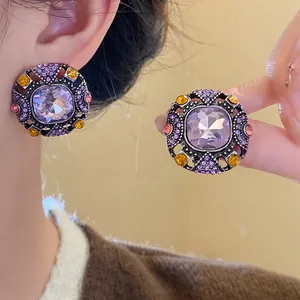Close-up detail of vintage square earrings with purple crystals and colorful rhinestones