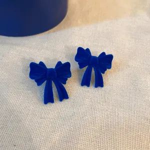 Vista dettagliata di orecchini a fiocco in velluto blu Klein vivace e morbido