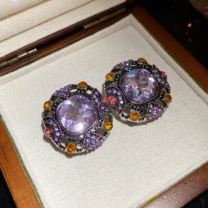Close-up of vintage square earrings with purple stones and colorful rhinestone accents.