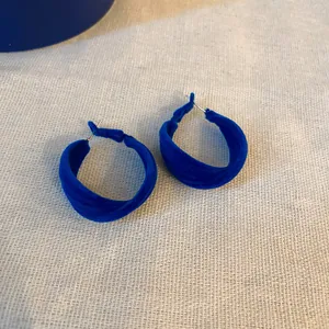 Vista dettagliata di orecchini a cerchio in velluto blu Klein con perni in argento