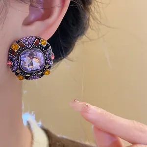 Detailed macro view of vintage court style purple crystal stud earring worn on person's ear