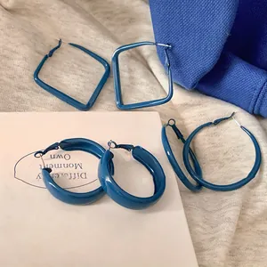 Détail de boucles d'oreilles bleu Klein peintes par pulvérisation, carrées et anneaux