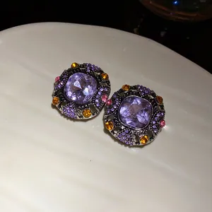 Detailed macro close-up of vintage square earrings with purple crystals and rhinestones.