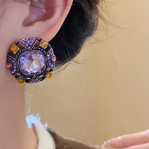 Detailed close-up showing a vintage square purple rhinestone stud earring on a model's ear