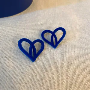 Dettaglio macro di orecchini a cuore in velluto blu Klein vintage con perni in argento vero