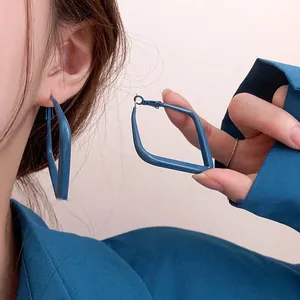 Détail en gros plan d'une boucle d'oreille créole géométrique bleu Klein épurée
