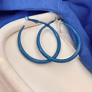 Gros plan de créoles bleu Klein peintes à la bombe sur un fond texturé très élégant