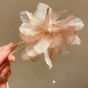 Close-up of a floral fabric hair fork with delicate pearl tassels held in hand.