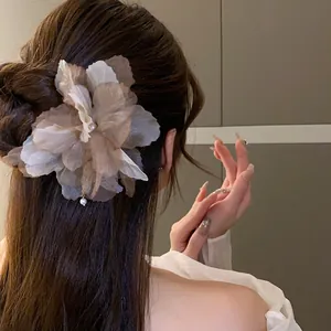 Close-up of elegant fabric flower hair pin with pearl tassel on styled hair bun