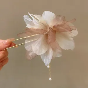 Close-up view of an elegant handmade fabric flower hair stick with delicate pearl tassels