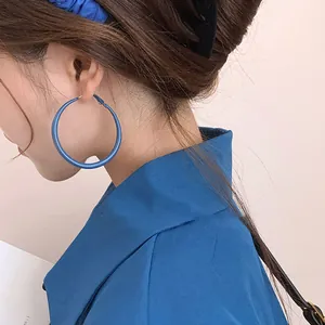 Détail en gros plan de grandes créoles bleu Klein mat portées par un mannequin