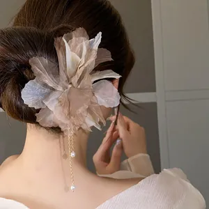 Close-up view of an elegant fabric flower hairpin with delicate pearl tassels in hair