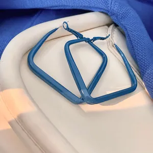 Gros plan sur les boucles d'oreilles créoles carrées bleu Klein avec des tiges en argent