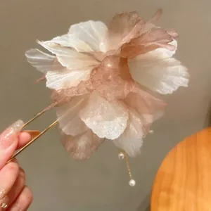 Close-up of elegant fabric flower hair fork with pearl tassel and translucent petals.
