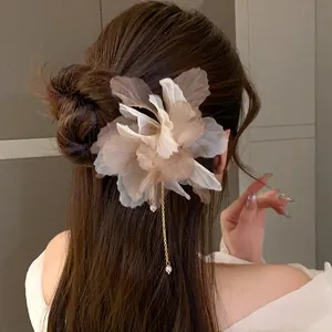 Detailed macro view of elegant fabric flower hair clip with pearl tassel on model's hair
