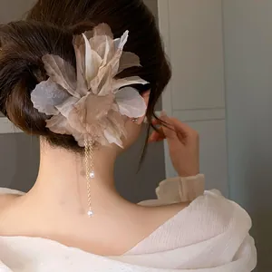 Elegant fabric flower hair clip with pearl tassels on a woman's updo hairstyle.