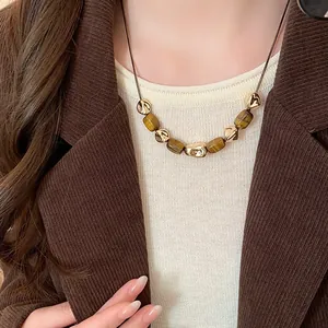 Close-up of vintage tiger eye stone necklace worn with a brown corduroy blazer