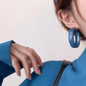Gros plan d'une boucle d'oreille créole minimaliste bleu Klein sur modèle