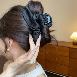 Detailed side view of an elegant black fabric rhinestone flower hair claw clip on a bun