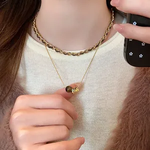 Close-up detail of layered vintage necklaces with tiger eye bead and gold chain jewelry
