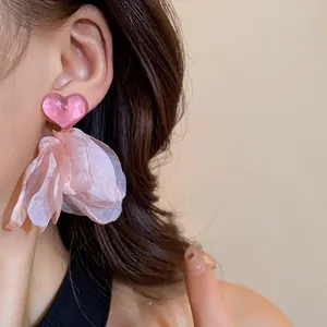 Detail shot of pink heart tassel earrings with soft fabric petals on an Asian model