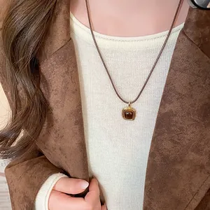 Close-up detail of a vintage square tiger eye pendant necklace with a golden frame finish