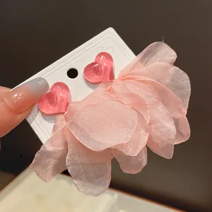 Macro view detail of pink heart stud earrings featuring delicate fabric petal tassels