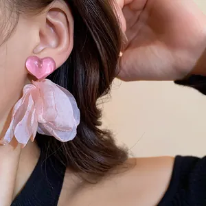 Detail shot of sweet pink heart earrings with delicate fabric petal tassels for elegant women.