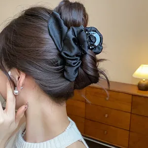 Close-up of black fabric flower hair claw clip with delicate rhinestone details