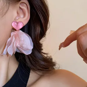 Detailed view of sweet pink heart earrings with flowing fabric petals on female model