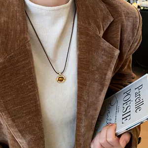 Detailed macro view of vintage round tiger eye stone necklace worn with brown velvet blazer