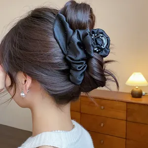 Detail view of a black rhinestone flower hair claw clip worn in an elegant updo hairstyle