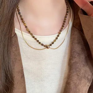 Close-up of a vintage brown tiger eye bead layered necklace on a model in a brown jacket