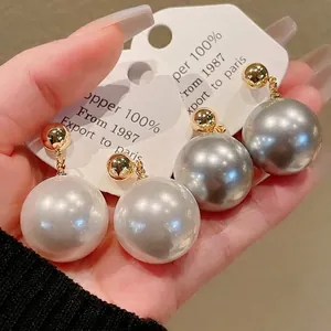 Boucles d'oreilles vintage en perles avec clous plaqués or sur carte de présentation