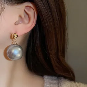 Élégante boucle d'oreille pendante grosse perle grise avec clou doré sur le modèle
