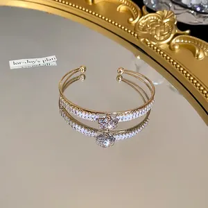 Elegant double-layer gold bangle with pavé-set clear zircons displayed on a mirrored surface