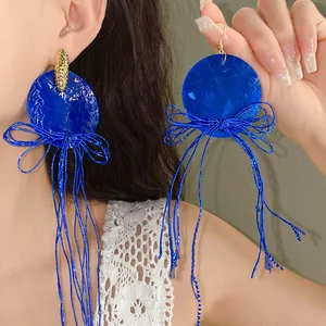 Nahaufnahme von leuchtend kleinblauen Schleifen-Ohrringen an einem Modell für Stil