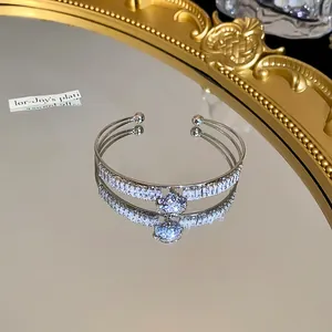 Close-up of elegant double-layer open bangle with sparkling zircons and water drop charm
