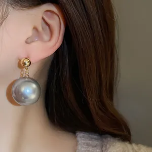 Gros plan détaillé d'une grande boucle d'oreille en perle grise sur le lobe d'un modèle
