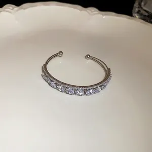 Close-up view of an elegant double-layer open bangle featuring pear-shaped clear zircons