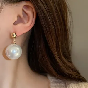 Vue détaillée de boucles d'oreilles pendantes en perles dorées de style vintage français.